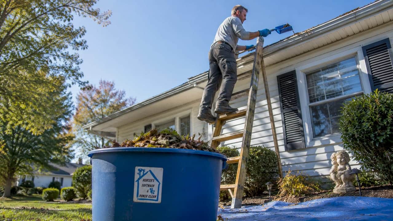 Homeowner safely cleaning gutters with proper gear